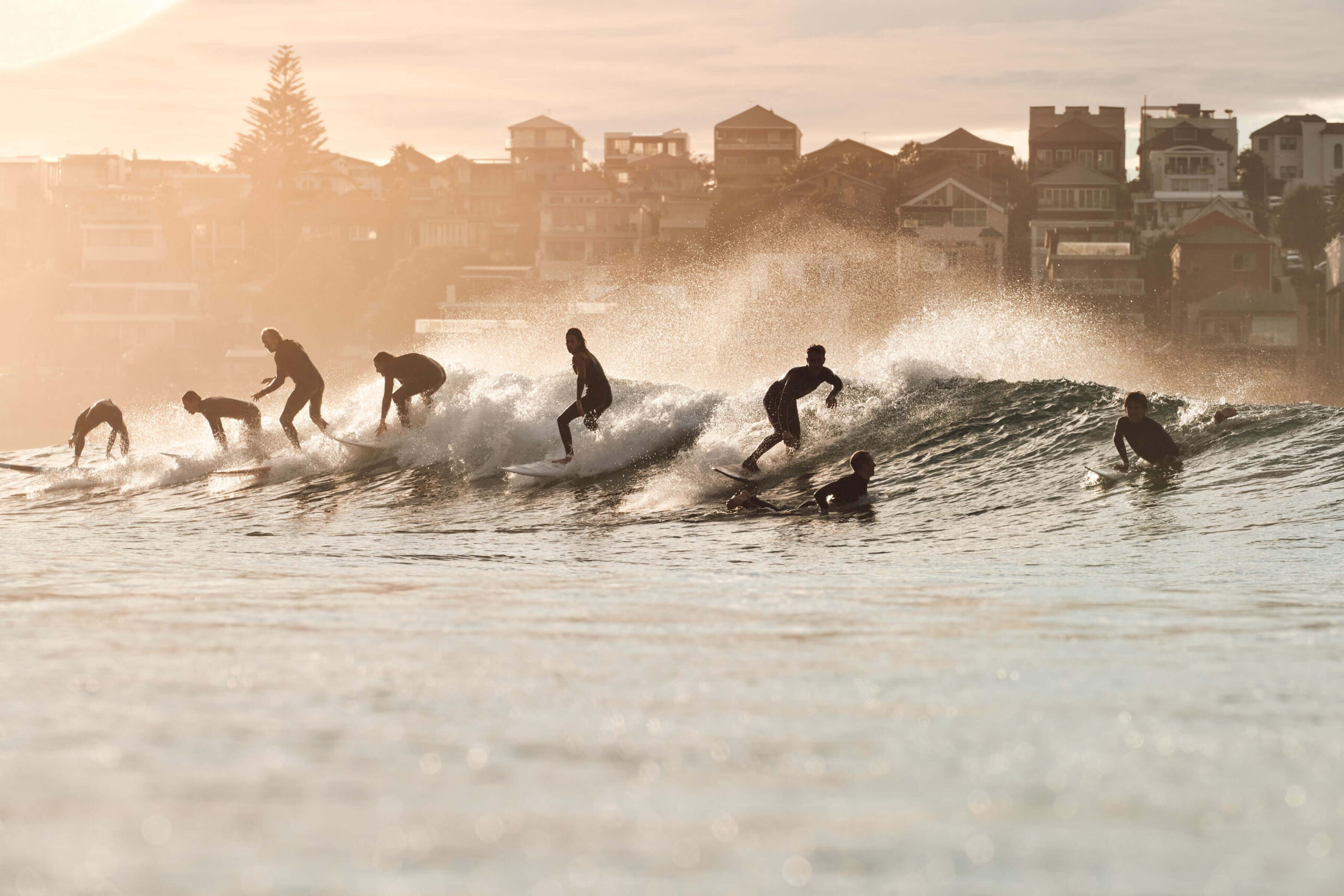 Surfers riding wave with city in background